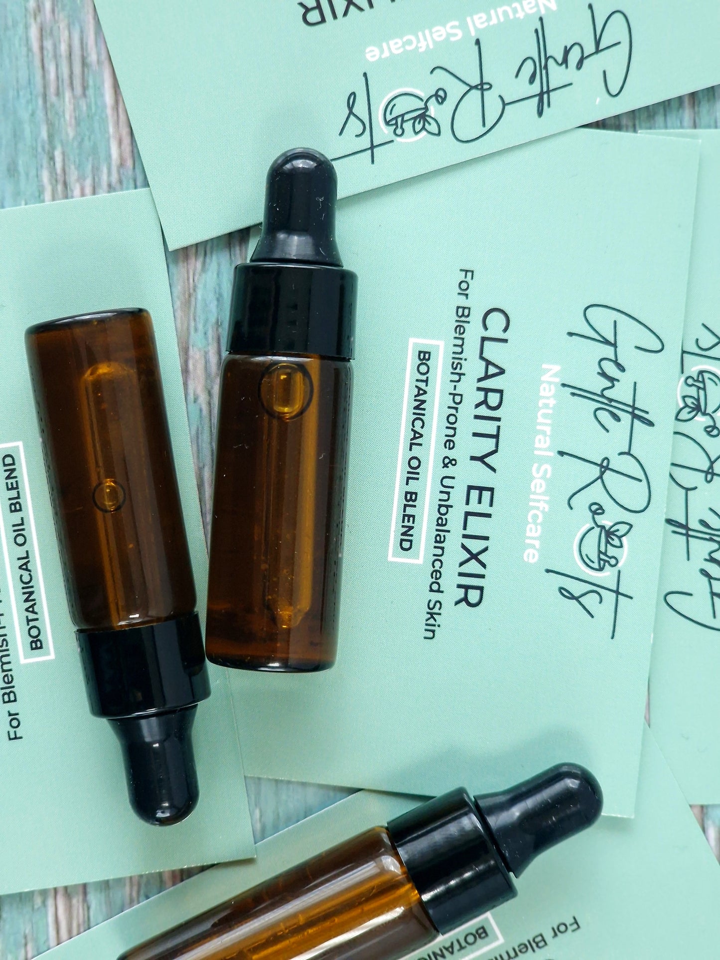 Mini Clarity Elixir for blemish prone and unbalanced skin with teal packaging and background card