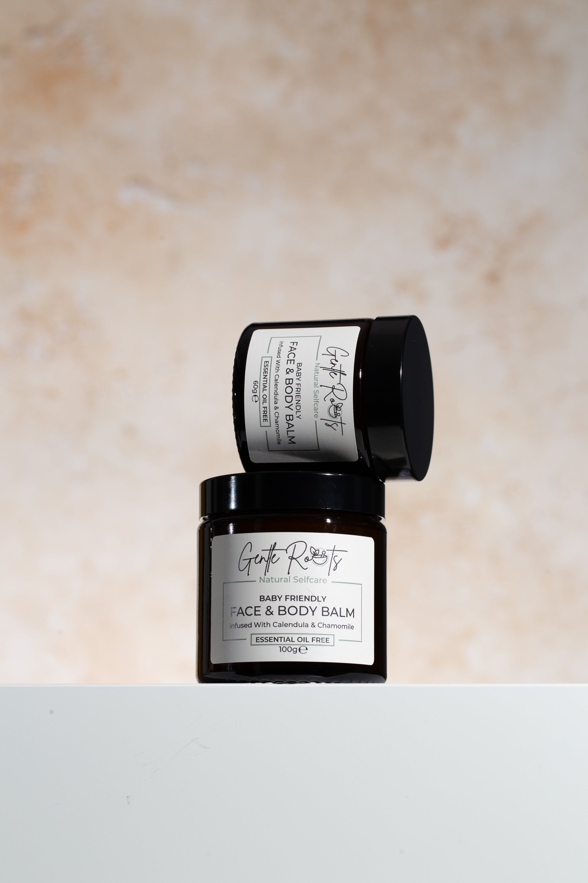 Gentle Roots Baby Friendly Face and Body Balm in amber glass jar on neutral stone background.