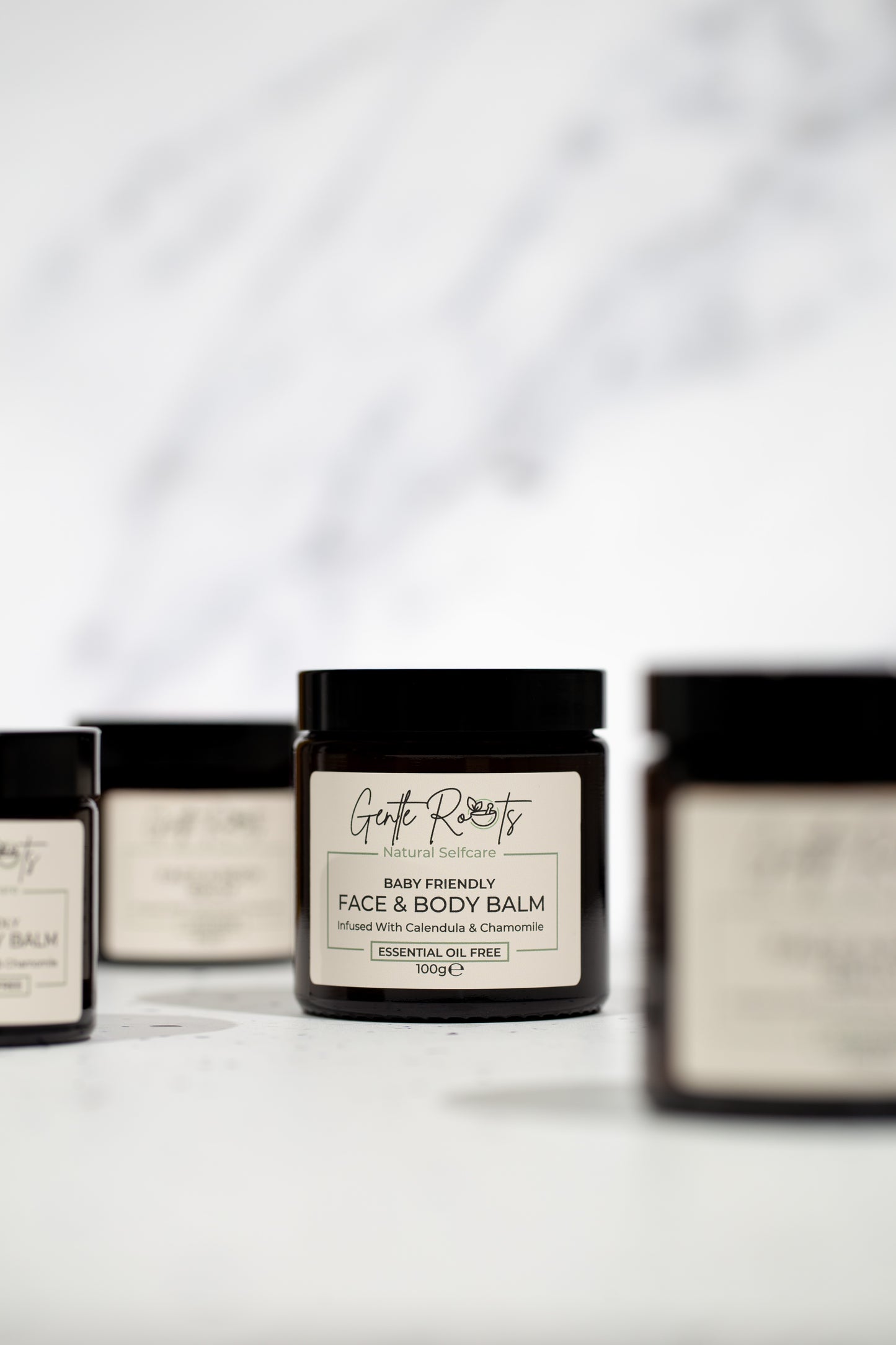 Gentle Roots Baby Friendly Face and Body Balm jars displayed in group on white surface.