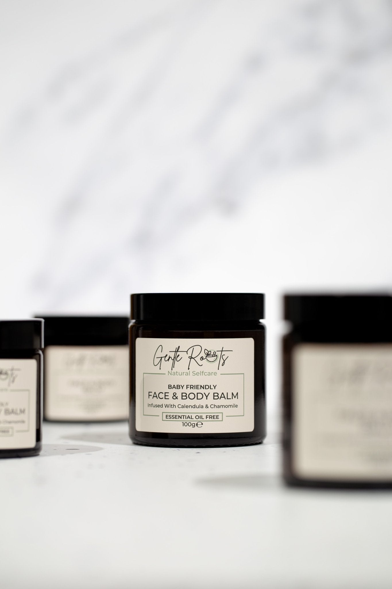 Gentle Roots Baby Friendly Face and Body Balm collection in amber glass jars on white background.