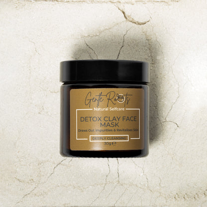 Gentle Roots Detox Clay Face Mask in amber glass jar on a background of powdered clay