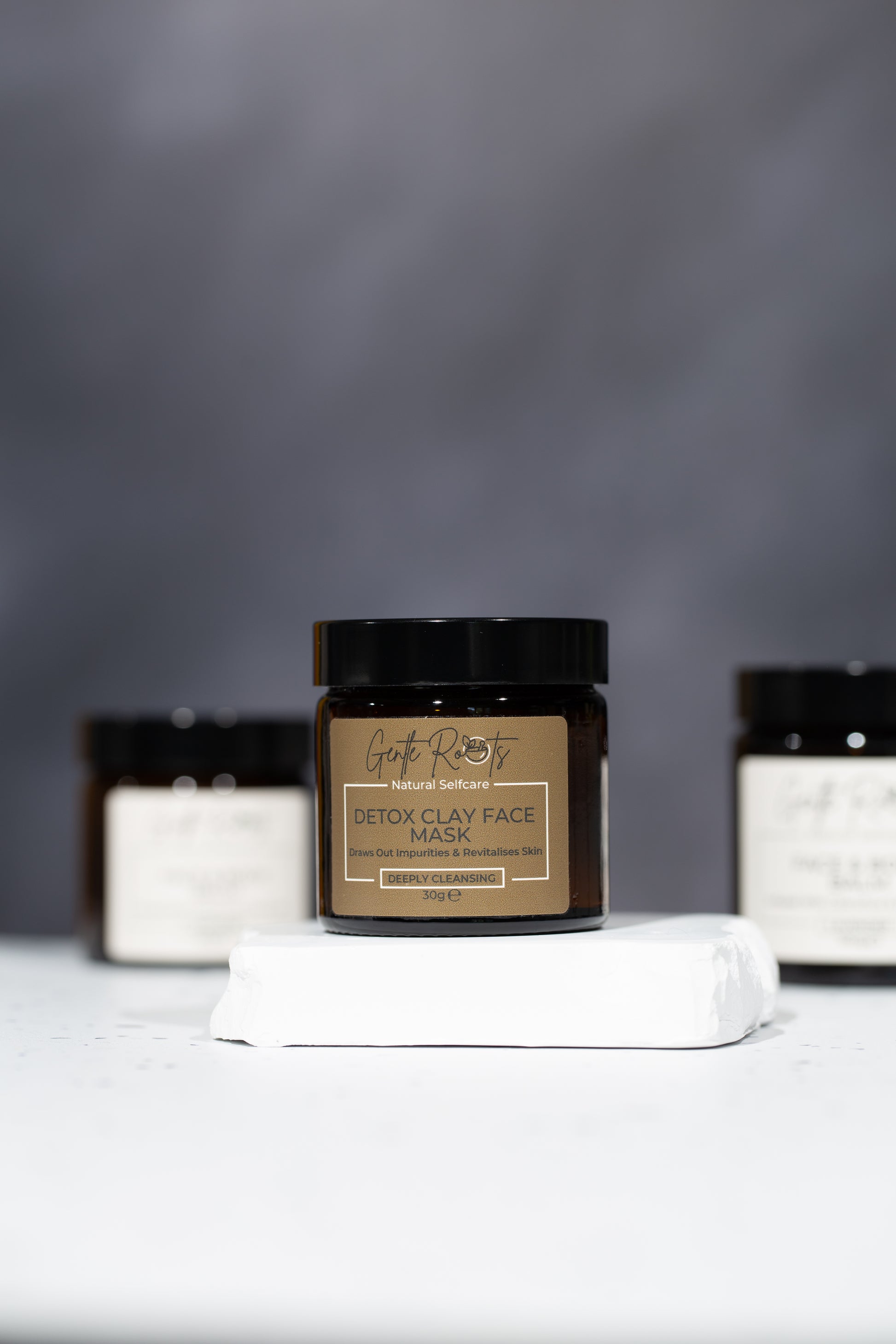Detox Clay Face Mask natural skincare jars on white surface with the Gentle Roots tallow balms in the background