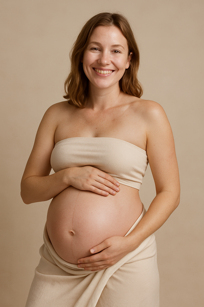 Pregnant woman holding bump holding a bottle of Gentle Roots Perineum Massage Oil for birth prep