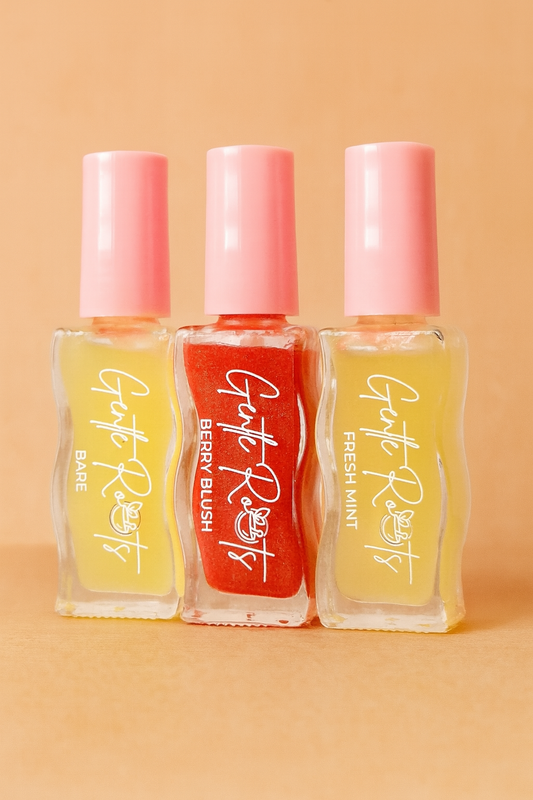Gentle Roots Nourish Lip Oil trio — Clear, Peppermint, and Strawberry Tinted in glass bottles with pink caps on beige background.