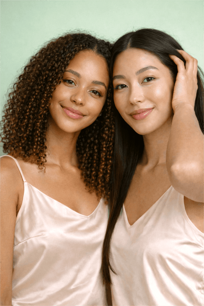 Two models with healthy curly and straight hair posed together on a mint green background, representing Gentle Roots Root Care Hair and Scalp Oil for balanced scalp and hair nourishment.